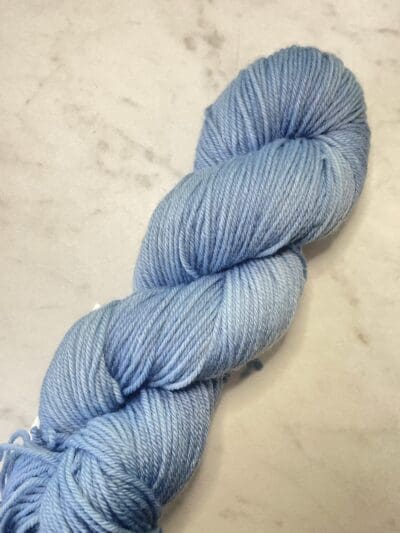 Blue Colorway: Variegated Cornflower. Length: 437 yds / 400 meters. 100 g Variegated Cornflower DK yarn, a naturally dyed blend of 75% Superwash Merino and 25% nylon. This Peru-origin yarn is hand-dyed using plant-based dyes, resulting in an eco-friendly option. Perfect for knitting or crocheting projects. <strong>While our team hand-dyes each skein with the utmost care, natural dyes results can vary based on plant materials and fibers. Please be aware that variations in color and appearance may vary f</strong>  