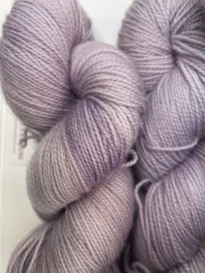 Purple Colorway: Variegated Light Lavender. Length: 399 yds / 365 Meters 100g Variegated Light Lavender 2-ply Fingering yarn, a naturally dyed soft purple blend made from 80% Superwash Merino Wool and 20% Recycled Nylon. This Peruvian-made yarn is both eco-friendly and luxurious. Its soft texture and vibrant color make it perfect for creating beautiful knit or crochet projects. Care Instructions: Hand wash in cold water with a gentle detergent made specifically for washing wool and other fine fibers, or a PH-neutral, dye free detergent. Lay flat to dry. Length: 399 yds / 365 Meters. 100 grams. <strong>While our team hand-dyes each skein with the utmost care, natural dyes results can vary based on plant materials and fibers. Please be aware that variations in color and appearance may vary from the display image.  </strong>