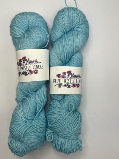 Blue Colorway: Variegated River Orchid. Length: 437 yds / 400 meters. 100g. Variegted River Orchid Sock yarn, a 4-ply naturally dyed variegated blue-green blend of 75% Superwash Merino and 25% nylon. This Peru-origin yarn is hand-dyed using plant-based dyes, resulting in an eco-friendly option. Perfect for knitting or crocheting projects. Care Instructions: Hand wash in cold water with a gentle detergent made specifically for washing wool and other fine fibers, or a PH-neutral, dye free detergent. Lay flat to dry. While our team hand-dyes each skein with the utmost care, natural dyes results can vary based on plant materials and fibers. Please be aware that variations in color and appearance may vary from the display image.  Please wash before using, as naturally dyed fibers can run the first few washings. Please be aware that variations in color and appearance may vary from the display image.  