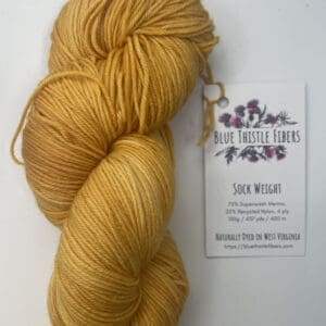 a yellow/gold yarn on a white surface