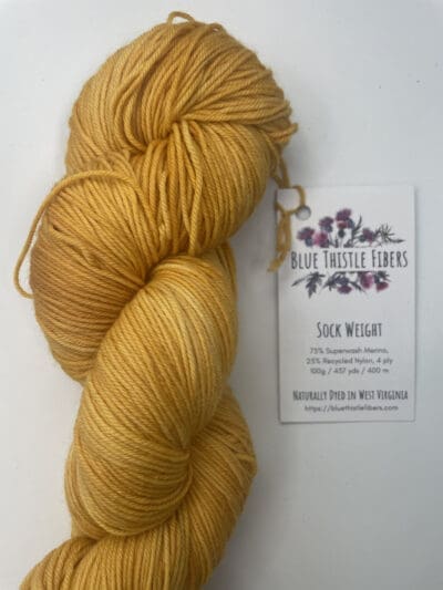 a yellow/gold yarn on a white surface