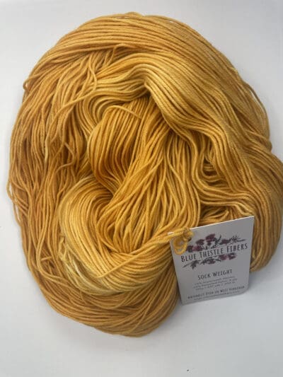 Yellow Colorway: Variegated Dark Gold. Length: 437 yds / 400 meters. 100 Grams. Variegated Dark Gold Sock 4-ply sock yarn, a naturally dyed blend of 75% Superwash Merino and 25% nylon. This Peru-origin yarn is hand-dyed using plant-based dyes, resulting in an eco-friendly option. Perfect for knitting or crocheting projects. Care Instructions: Hand wash in cold water with a gentle detergent made specifically for washing wool and other fine fibers, or a PH-neutral, dye free detergent. Lay flat to dry. <strong>While our team hand-dyes each skein with the utmost care, natural dyes results can vary based on plant materials and fibers. Please be aware that variations in color and appearance may vary from the display image.  </strong>  