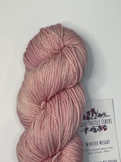 Pink Colorway: Variegated Rose. 219 yards / 200 meters. 100 grams Variegated Rose Worsted 4-ply  yarn is naturally dyed with sustainably harvested/foraged dye material from plants, minerals, roots, trees, and other organic materials. Blue Thistle Fiber’s 4-ply Worsted yarn is certified mulesing-free SW 100% Merino wool and quickly works up into hats and sweaters everyone will love to wear. A durable yarn that holds up to washing and wearing. Care Instructions: Machine wash on a gentle cycle using mild detergent. Do not bleach. Dry flat away from direct sunlight. <strong>While our team hand-dyes each skein with the utmost care, natural dyes results can vary based on plant materials and fibers. </strong><strong>Please wash before using, as naturally dyed fibers can run the first few washings.</strong> <strong>Please be aware that variations in color and appearance may vary from the display image.</strong>  