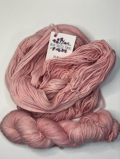 Pink Colorway: Rose. Length: 246 yds / 225 meters. 100 Grams. Our Variegated Rose DK wool yarn is a naturally dyed variation in our pink colorway.  This 4-ply yarn has the perfect combination of warmth and durability. 75% Superwash Merino wool / 25% Recycled Nylon, sourced directly from Uruguay, has excellent insulation properties and adds structure, that provides the strength and lightness it needs for heavy-duty wear. Our naturally dyed DK yarn is an excellent choice for soft and durable sweaters, baby clothes, and boot socks, just to name a few possible uses for this versatile yarn. Machine washable and easy to care for. Care Instructions: Machine wash on a gentle cycle using mild detergent. Do not bleach. Dry flat away from direct sunlight. While our team hand-dyes each skein with the utmost care, natural dyes results can vary based on plant materials and fibers. Please be aware that variations in color and appearance may vary from the display image.